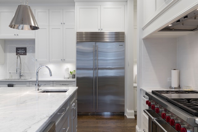 A modern kitchen in a westlake village rental with stainless steel appliances white marble countertops white cabinets and a large center island